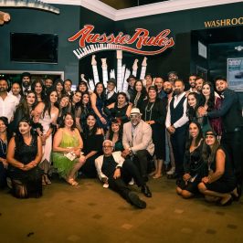 Raman Bedi et al. standing in front of a crowd posing for the camera